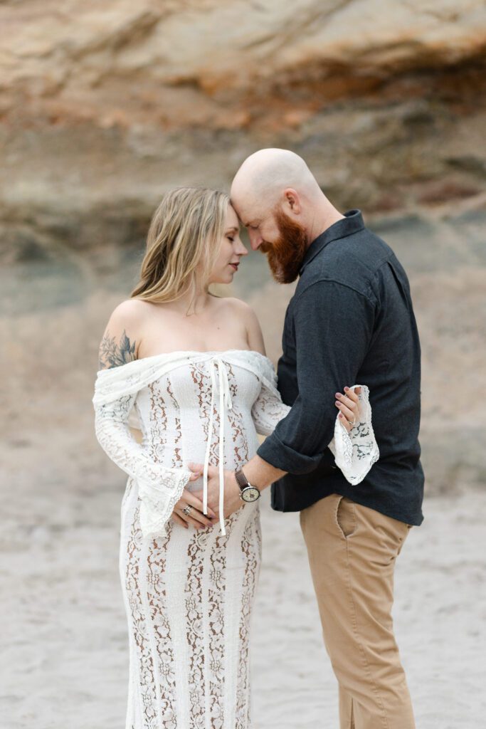 Couple embraces wife's pregnant belly as they relax into a portrait for their maternity photos, Portland.