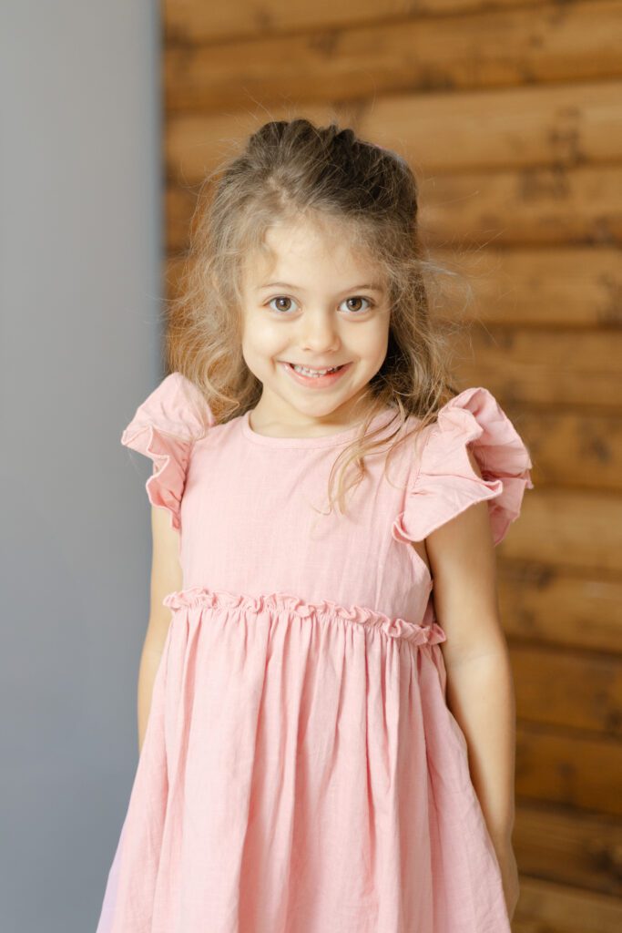 Smiling portrait of girl wearing pink dress.