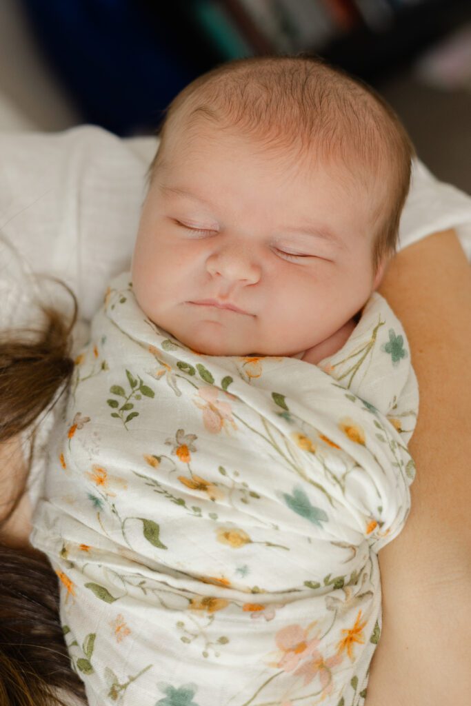 Baby swaddled in mother's arms during newborn portrait session.