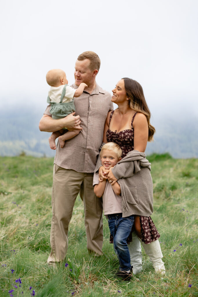 Family stands together with misty mountain backdrop, for family portraits.