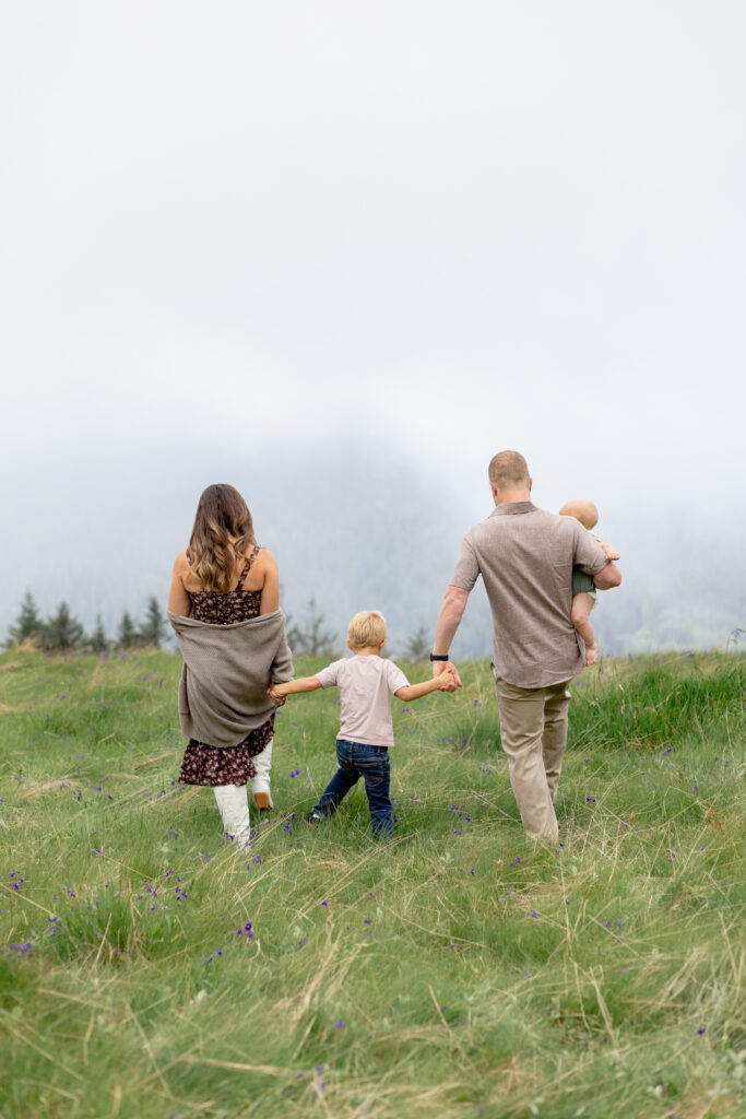 Lifestyle family photoshoot with family holding hands and walking through a misty, grassy field