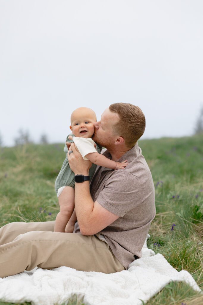 Father kisses young baby on the cheek during family photos, Portland.