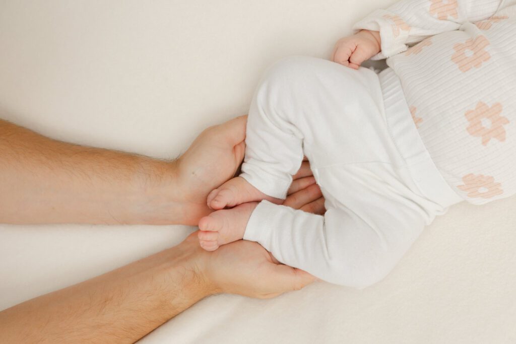 Father cups his newborn baby's feet in his hands for newborn portraits.
