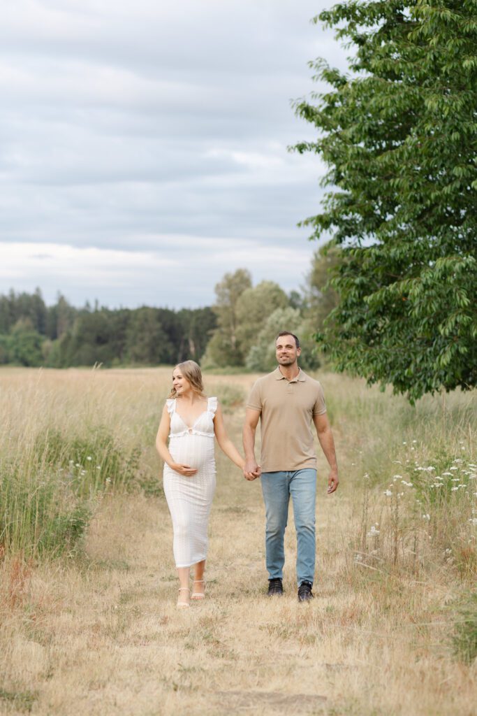 Portland lifestyle family photographer captures couple walking through golden grassy field.
