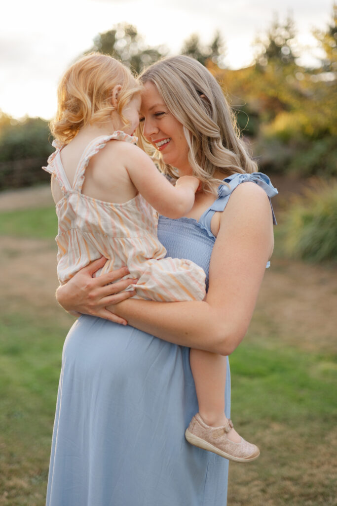 Expectant mother holds her young child close for a sunset maternity session.