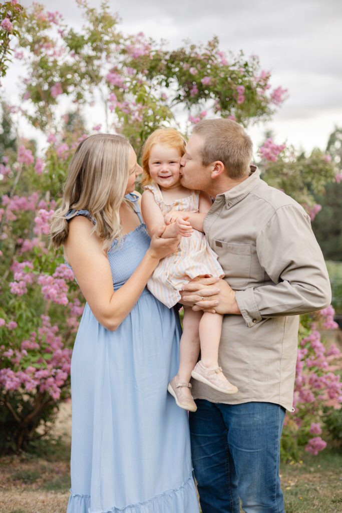 Parents hug their smiling daughter for this spring family photoshoot.